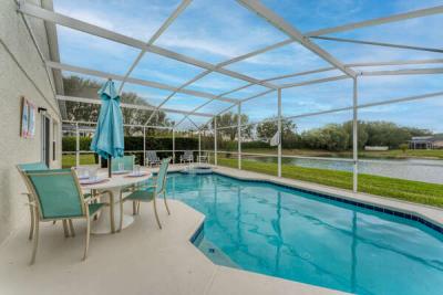 Screened private pool with patio dining set, lounge seating, and peaceful water views-perfect outdoor relaxation.