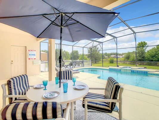 Outdoor dining under covered lanai overlooking the pool