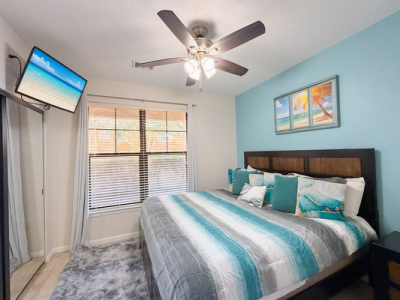 Coastal-themed king bedroom in an Orlando vacation rental with ceiling fan and wall-mounted TV.