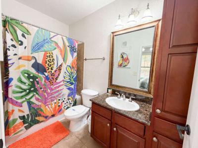 Full bathroom in an Orlando vacation rental with tub, granite vanity, and colorful tropical shower curtain.