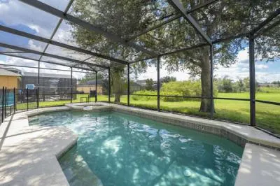 Pool showing screen enclosure and spa overlooking wide grassy area