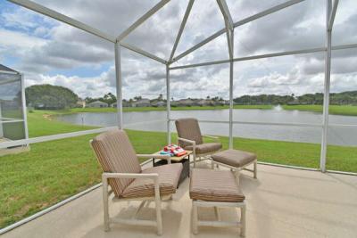 Screened patio seating area with cushioned chairs overlooking a lake view.