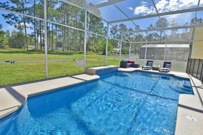 Screened in private pool with patio seating and wooded backyard.