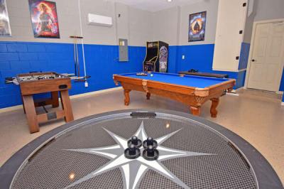 Themed game room with air hockey table, pool table, foosball table, and arcade machine.