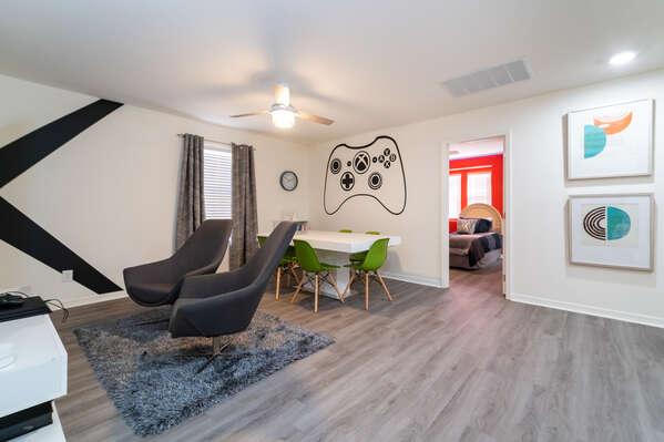 Upstairs game loft with lounge seating, gaming table, and controller wall mural.