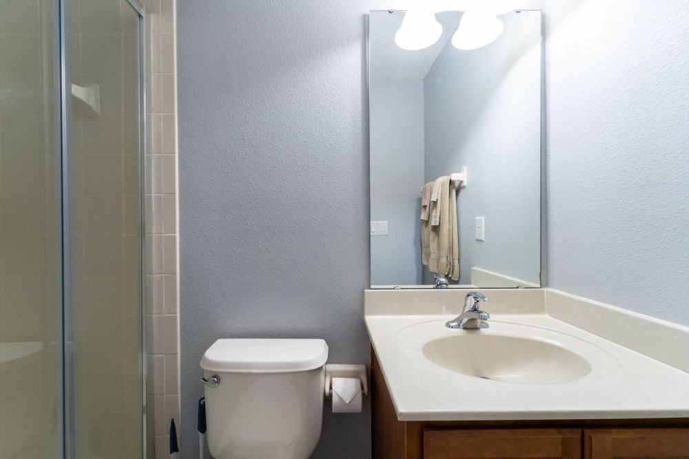 Upstairs en-suite bathroom with walk in shower, vanity sink, and toilet.