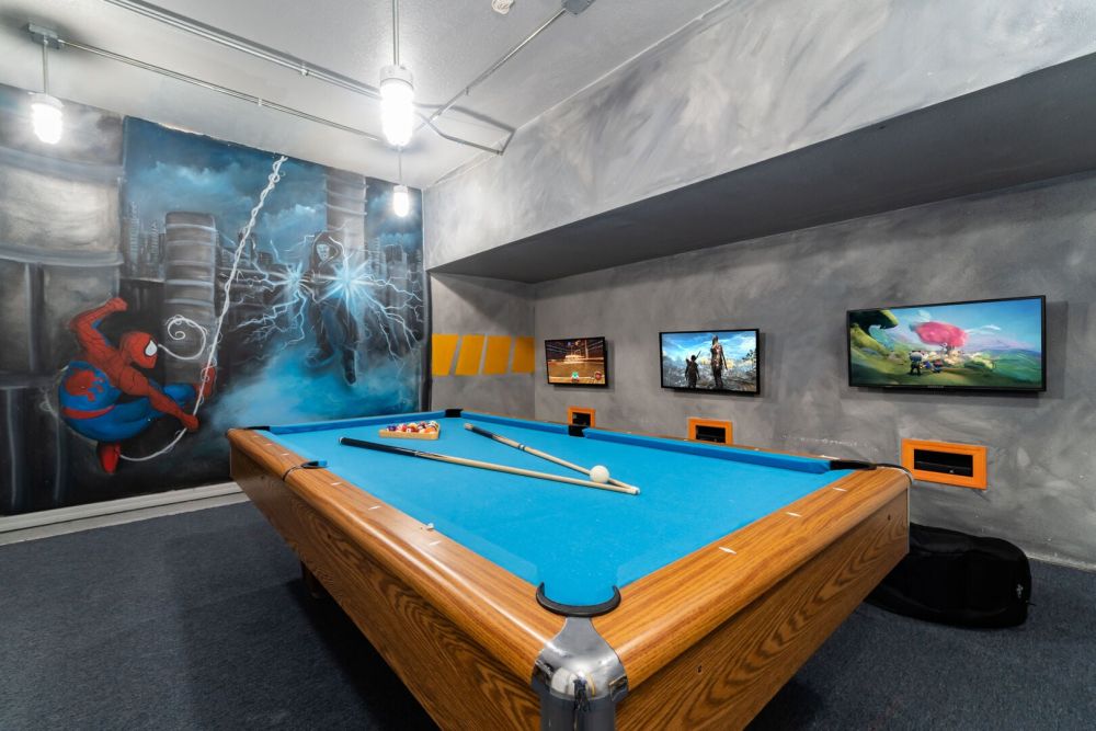 Game room featuring a pool table, wall mounted TVs, and colorful superhero themed artwork.