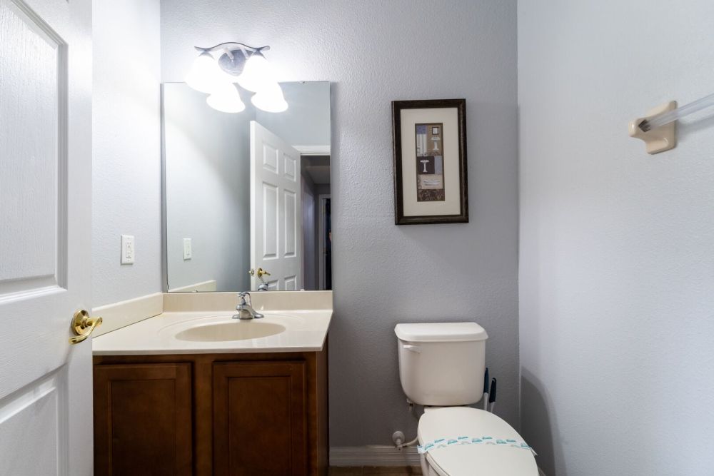 Downstairs shared bathroom featuring a single sink vanity, mirror, and toilet.