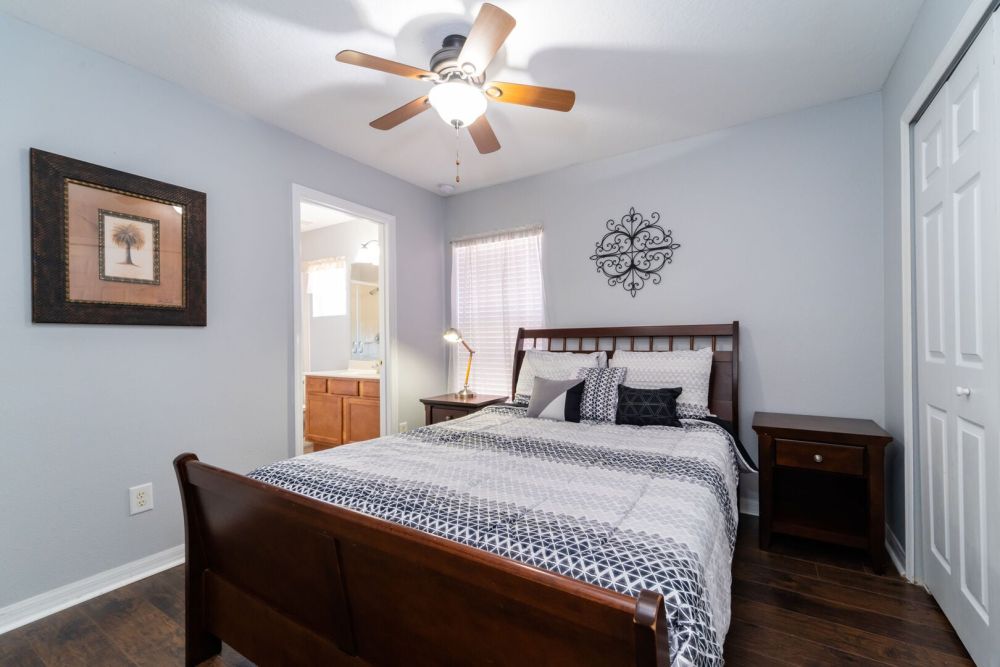 Upstairs bedroom with queen bed, ceiling fan, nightstands, and en-suite bathroom access.