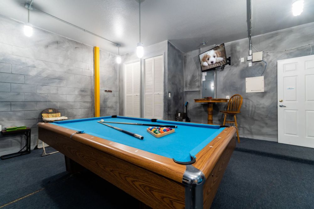 Game room with pool table, wall mounted TV, and seating area.
