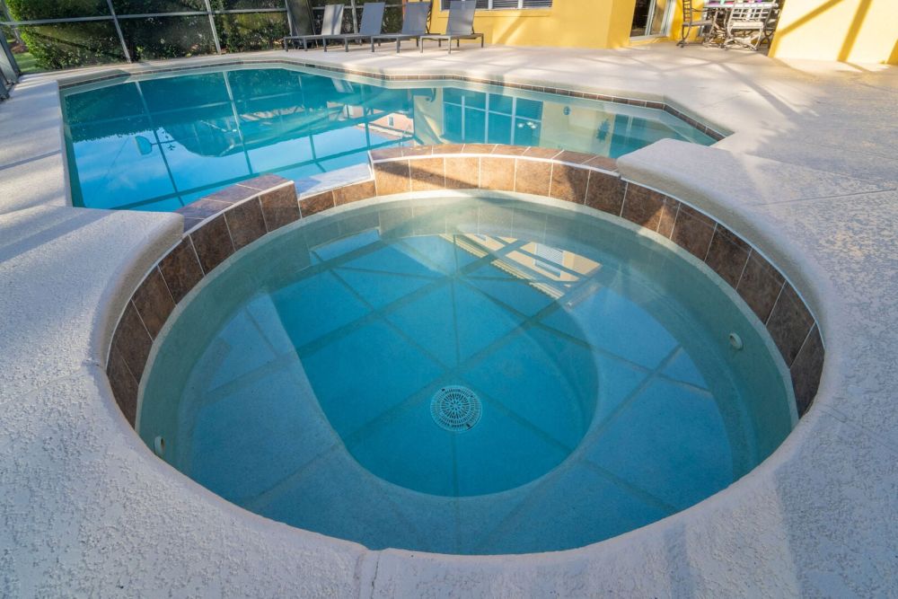 Private pool and spa with connected swimming pool in screened patio.