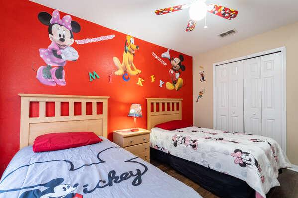 Upstairs themed kids bedroom with two twin beds, colorful wall murals, ceiling fan, and hardwood flooring.