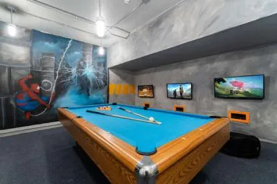 Game room featuring a pool table, wall mounted TVs, and colorful superhero themed artwork.