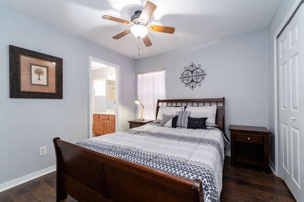 Upstairs bedroom with queen bed, ceiling fan, nightstands, and en-suite bathroom access.