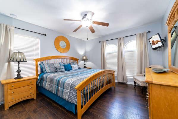 Upstairs second master bedroom with king bed, ceiling fan, wall mounted TV, and hardwood floors.