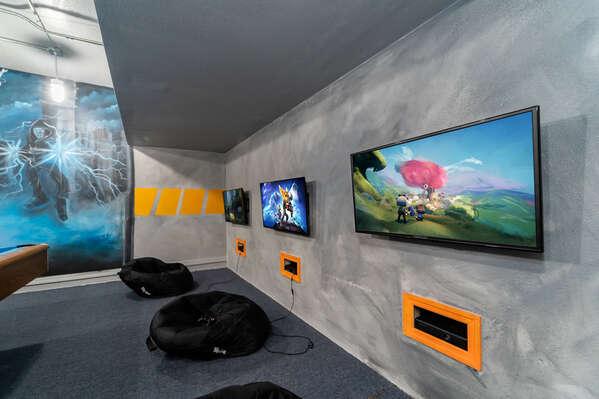 Themed games room with wall mounted TVs, gaming stations, and floor seating.