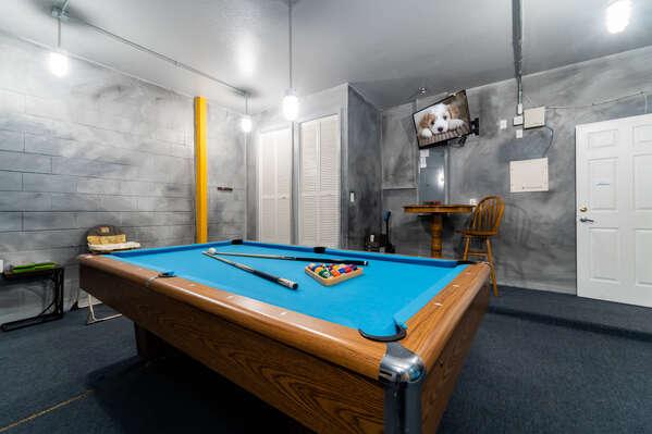 Game room with pool table, wall mounted TV, and seating area.