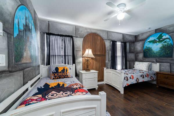Upstairs themed twin bedroom with two beds, decorative wall murals, ceiling fan, and playful character bedding.