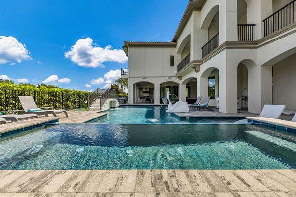 Relax by the sparkling private pool featuring soothing fountains, in-pool loungers, and a built-in slide for kids.